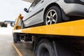 Broken car on flatbed tow truck being transported for repair Royalty Free Stock Photo