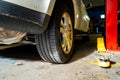 Broken down car in a mechanic shop, near a jack lift, showing the bottom wheel and tire of the car parked in the garage repair