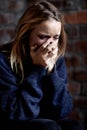 Broken down emotionally. Abused young woman crying hard and covering her mouth.