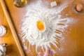 Broken egg on flour with baking tools