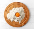 Broken egg in flour on cutting board