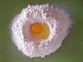 Broken egg on flour on green background, means for making bread Royalty Free Stock Photo