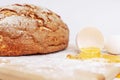 Broken egg on a floured wooden board on a background of appetizing fresh round bread. Homemade baking. Close-up Royalty Free Stock Photo