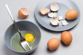 Broken egg and fork in gray bowl. Chicken shells on gray plate. Two brown eggs on table Royalty Free Stock Photo
