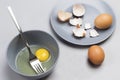 Broken egg and fork in gray bowl. Chicken shells on gray plate. Two brown eggs on table Royalty Free Stock Photo