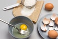 Broken egg and fork in gray bowl. Flour and sieve on paper. Chicken shells on gray plate Royalty Free Stock Photo