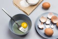 Broken egg and fork in gray bowl. Flour and sieve on paper. Chicken shells on gray plate Royalty Free Stock Photo
