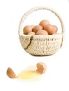 A broken egg near basket of eggs