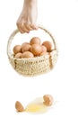 A broken egg near hand with basket of eggs