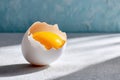Broken egg revealing its yolk on a textured surface with dramatic lighting Royalty Free Stock Photo