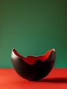 Broken egg shell painted in black and red, with green background. Royalty Free Stock Photo