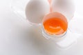 Broken egg with whole eggs in a transparent plastic container on white wooden background Royalty Free Stock Photo