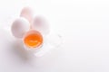 Broken egg with whole eggs in a transparent plastic container on white wooden background Royalty Free Stock Photo