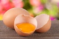 Broken egg with yolk and eggshell On a wooden table with a blurry garden background Royalty Free Stock Photo