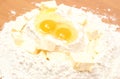 Broken eggs in flour and cube of margarine lying on table