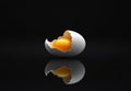 Broken eggshell with raw egg on a black minimalist surface reflective background Royalty Free Stock Photo