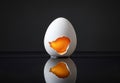 Broken eggshell with raw egg on a black minimalist surface reflective background Royalty Free Stock Photo