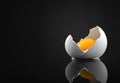 Broken eggshell with raw egg on a black minimalist surface reflective background Royalty Free Stock Photo