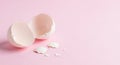 Broken eggshells are arranged on a pastel pink surface. The shells are split into t Royalty Free Stock Photo
