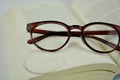 Broken eyeglasses with missing lens lying on an open book representing damaged eyewear and the need for repair concept Royalty Free Stock Photo
