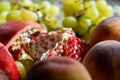 Broken fruit of pomegranate, lies on the table under the sun along with grapes and peaches