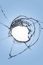 Broken glass with a hole in the center on a blue background. The effect of cracks on the window. Royalty Free Stock Photo