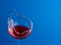 Broken glass with red wine on a blue background Royalty Free Stock Photo