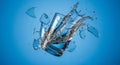 Broken glass tumbler exploding with dramatic water splash on blue Royalty Free Stock Photo