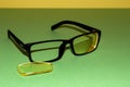 Broken glasses lie on a green surface. Nearby lies a yellow lens that has fallen out of the frame. Yellow background back Royalty Free Stock Photo