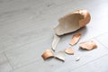 Broken golden ceramic vase on wooden floor  closeup. Space for text Royalty Free Stock Photo