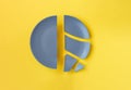Broken gray ceramic plate on yellow background Royalty Free Stock Photo
