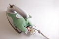 Broken green electric iron with access to the wires and the contact group in the back. Home appliance repair concept. Copy space.