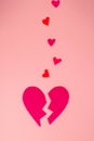 A broken heart. Felt heart divided into halves. Pink background, vertical orientation. Valentine's Day Concept