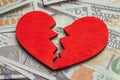 Broken heart because of money. Heart on a stack of cash dollars. Crack in the red heart, Breaking the relationship Royalty Free Stock Photo