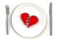 Broken heart on plate, knife and fork on white table