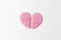 Broken heart shaped cookie with on pink background as a symbol of the end of the relationship. Loneliness, divorce, separation,