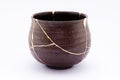 Broken Japanese handmade bowl restored with the antique japanese kintsugi real gold technique Royalty Free Stock Photo