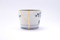 Broken Japanese handmade soba cup restored with the antique japanese kintsugi real gold technique Royalty Free Stock Photo