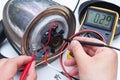 Broken kettle, concept. Person's hands repairing electric kettle with multimeter.