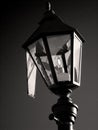 Broken lantern is lit against dark sky. Fractured Street lamp burning at night. Monochrome, dark colors Royalty Free Stock Photo