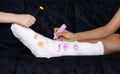 broken leg. bone damage. children paint plaster. girl boy paint a white bandage on his leg with colored markers
