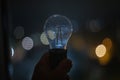 A broken light bulb in a hand against the backdrop of a nighttime city. Royalty Free Stock Photo