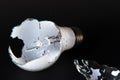 Broken light bulb isolated on black background with shattered piece of lightbulb. Royalty Free Stock Photo