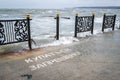 Broken metal fence on the sea embankment during a strong storm and the inscription on the pier - swimming is prohibited, no swimmi