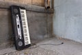 A broken musical synthesizer stands sent to the wall of a building at a city dump Royalty Free Stock Photo