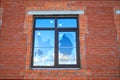 A broken new window on the wall of a red house that reflects the clouds and sky Royalty Free Stock Photo