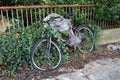 Broken old bicycle with twisted tyre and rusted parts left next to abandoned family house front metal fence