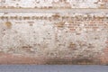 Broken old bricklaying wall from red white bricks with damaged plaster and road pavement background texture Royalty Free Stock Photo