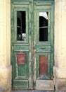 Broken old green doors in an abandoned derelict house with broken windows and faded peeling paint