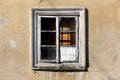 Broken old window with dilapidated antique vintage decorative white wooden frame mounted on cracked family house wall